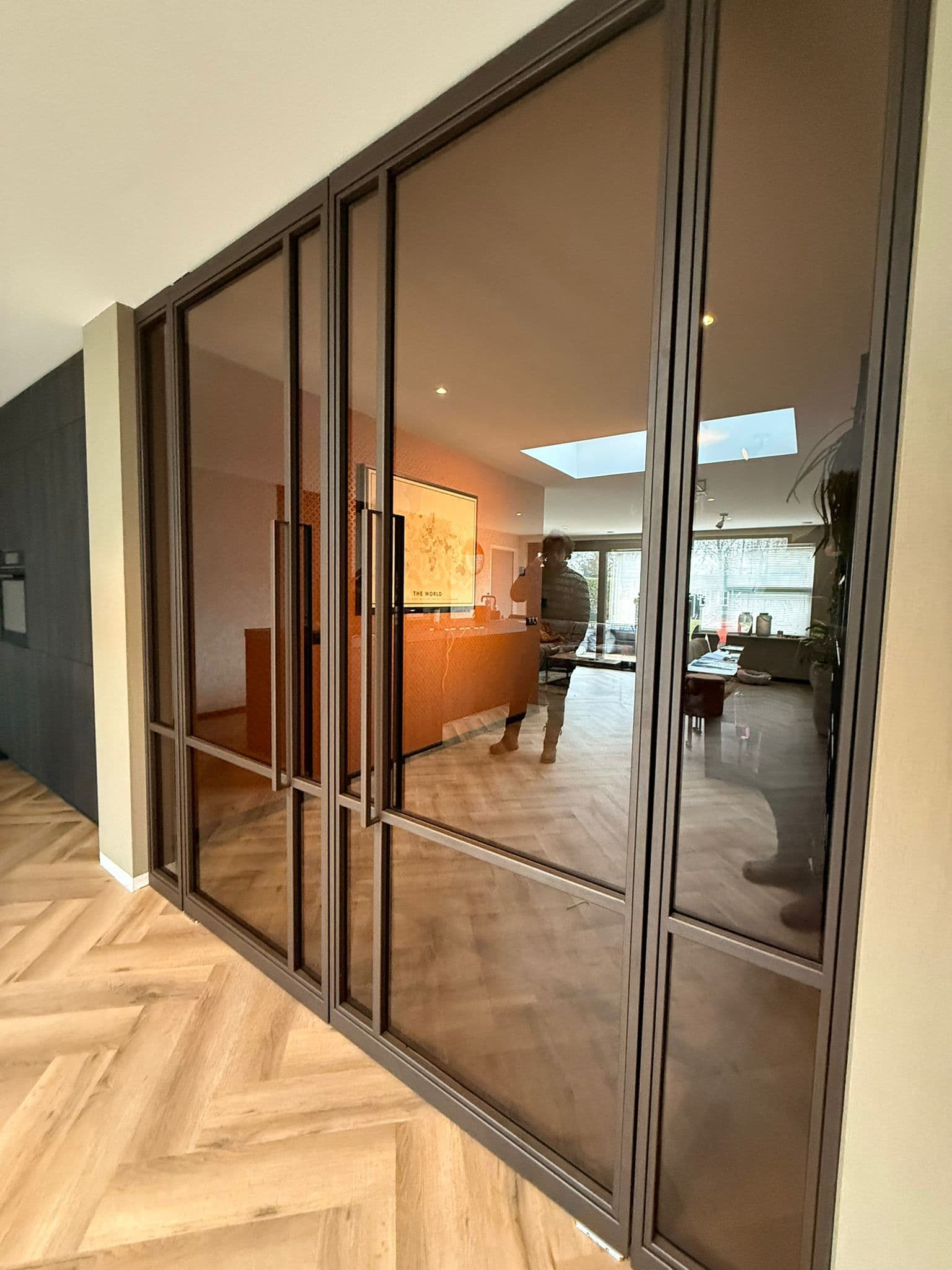 Luxe vierdelige stalen binnenpui in een warme bruine coating met sfeervol getint glas, gezien vanuit de open keuken.