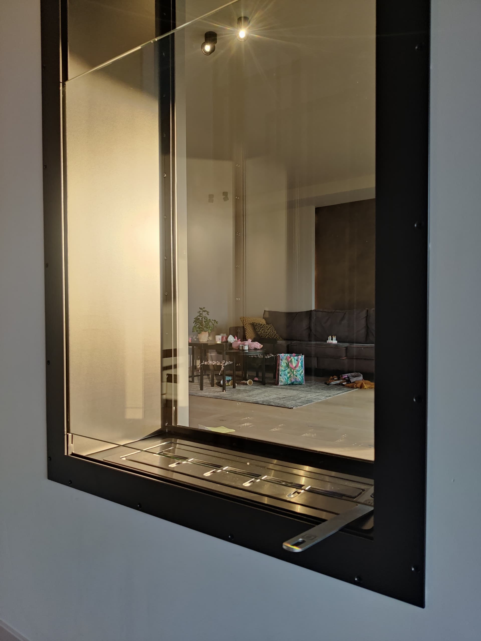 Zwart stalen binnenraam met doorkijk naar een woonkamer, met een radiator in dezelfde stijl onder het kozijn verwerkt.
