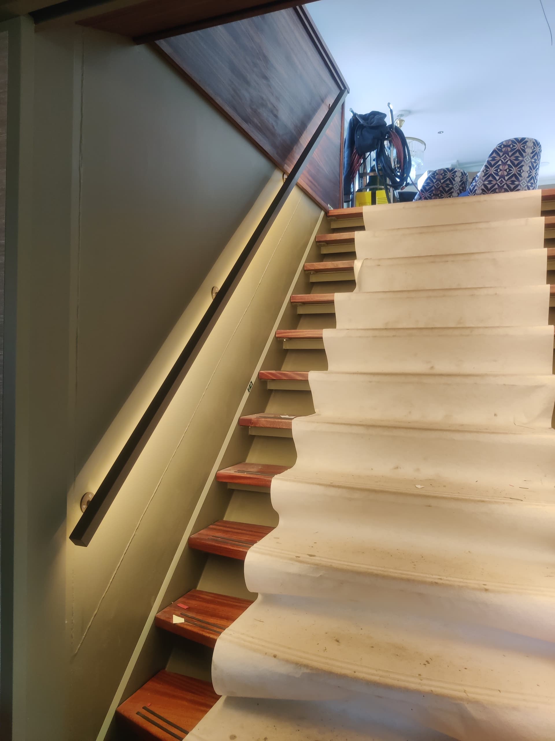 Bronzen stalen trapleuning met geïntegreerde ledverlichting en bijpassende roomdivider met geribbeld glas in een luxe scheepsinterieur.
