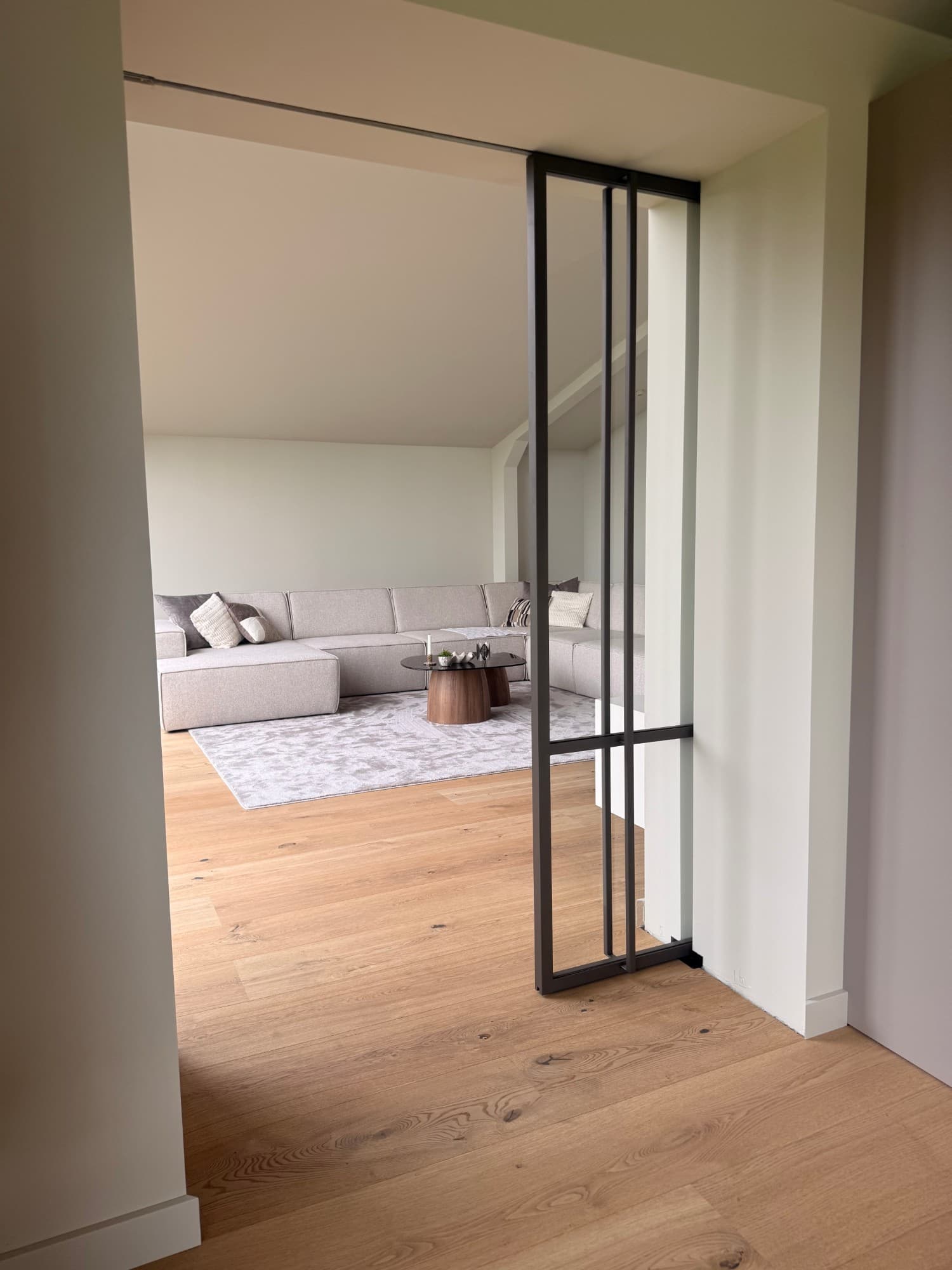 Bruine stalen pocket schuifdeur half in de wand geschoven, met de woonkamer vrij in beeld.