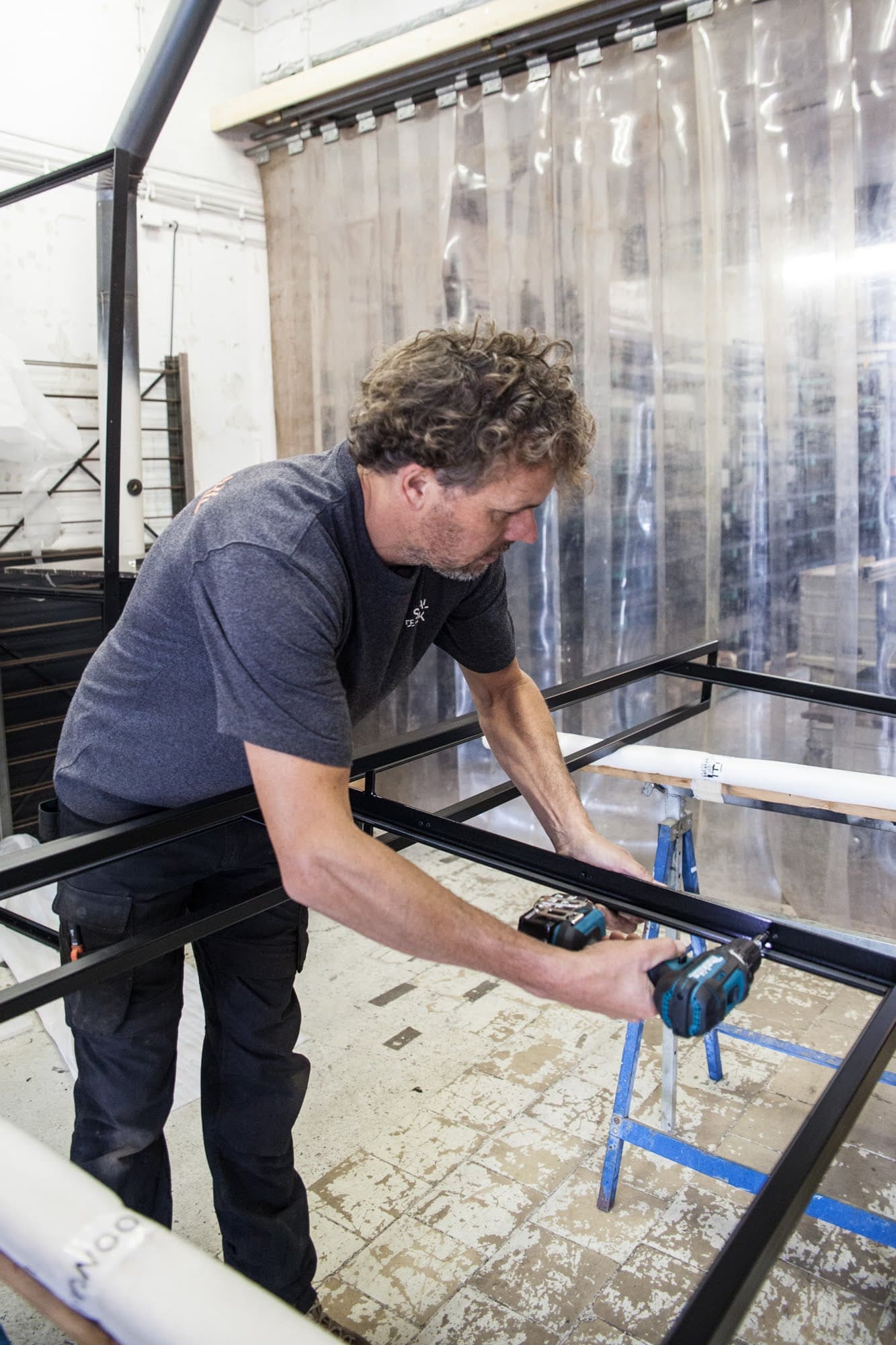 Monteur van de StaalZaak boort een stalen kozijn vast in de werkplaats.