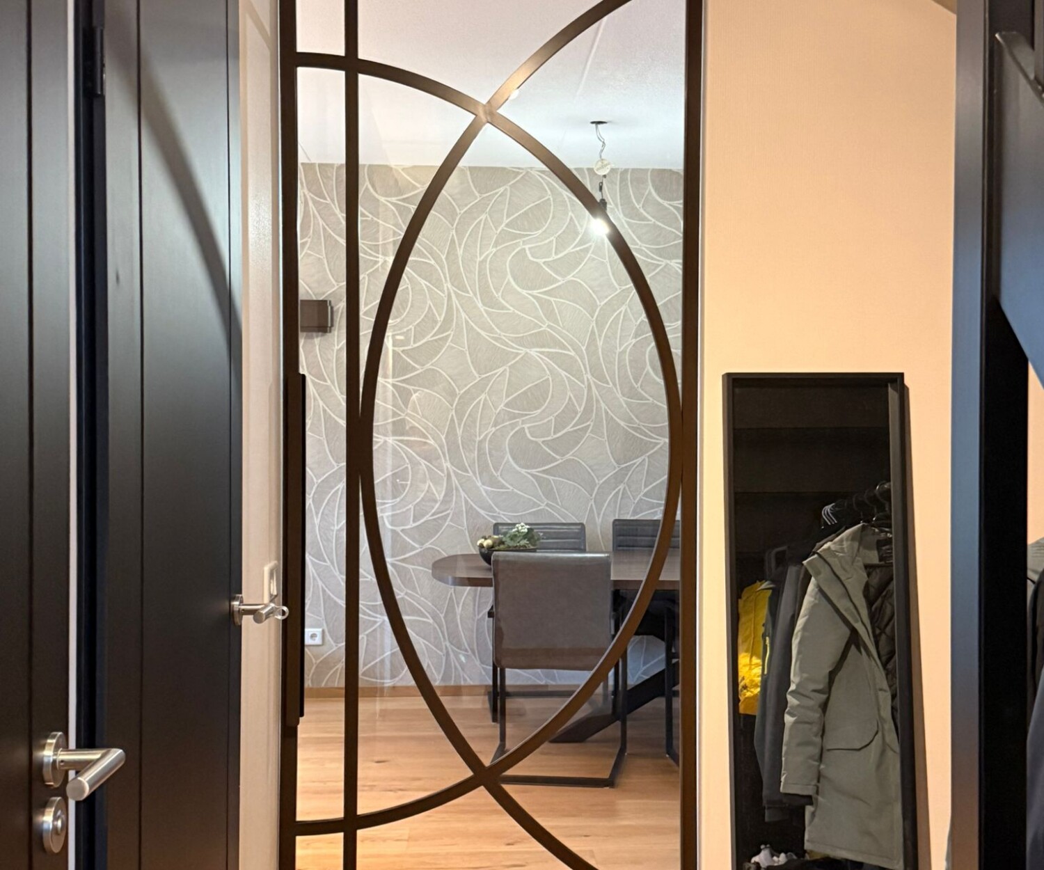 Gesloten kamerhoge bruine stalen taatsdeur met een exclusief organisch boogdesign tussen de hal en de eetkamer.