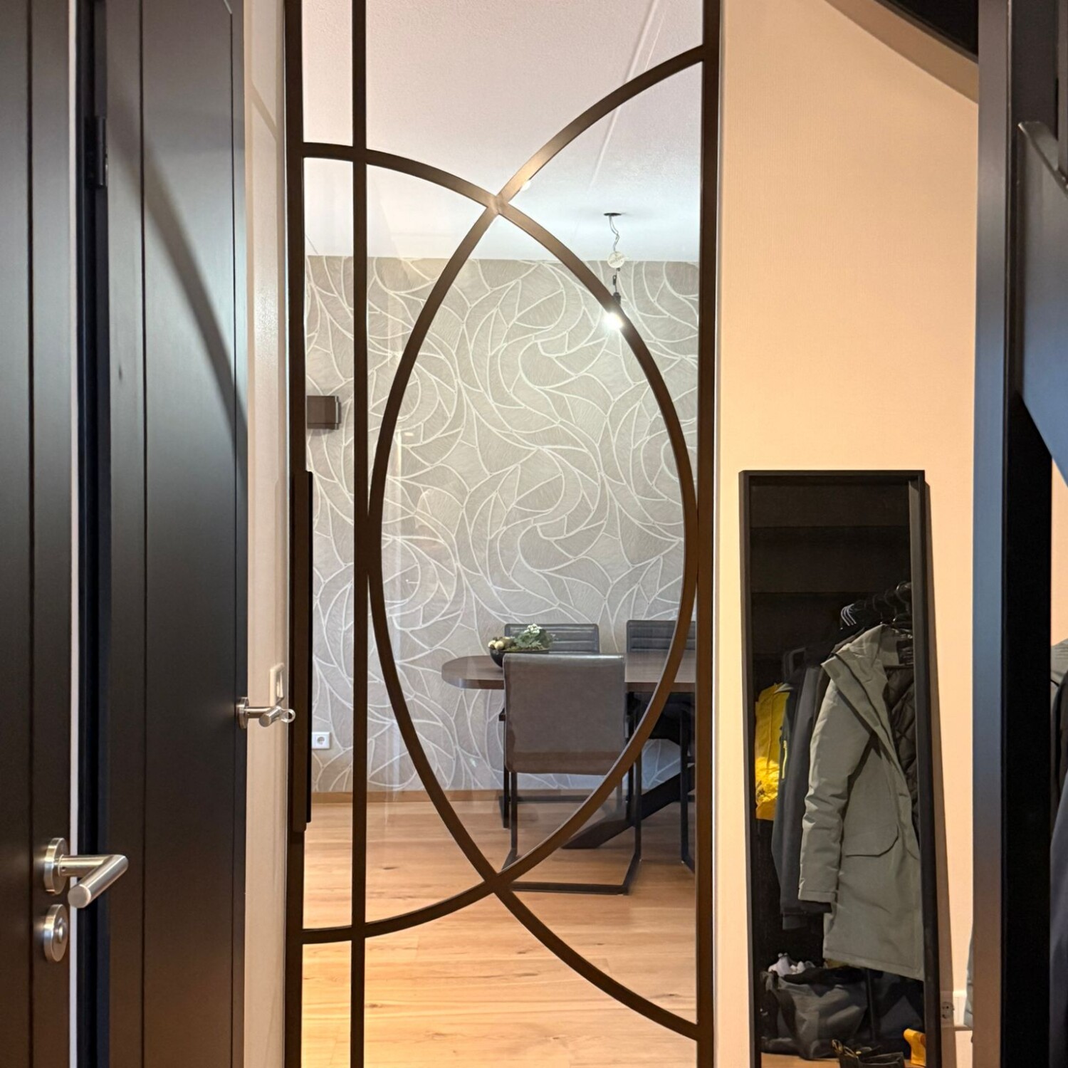 Gesloten kamerhoge bruine stalen taatsdeur met een exclusief organisch boogdesign tussen de hal en de eetkamer.