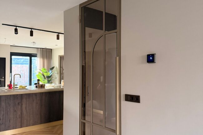 Luxe bruine stalen binnendeur met kozijn en bronskleurig glas, geplaatst naast een moderne houten keuken.