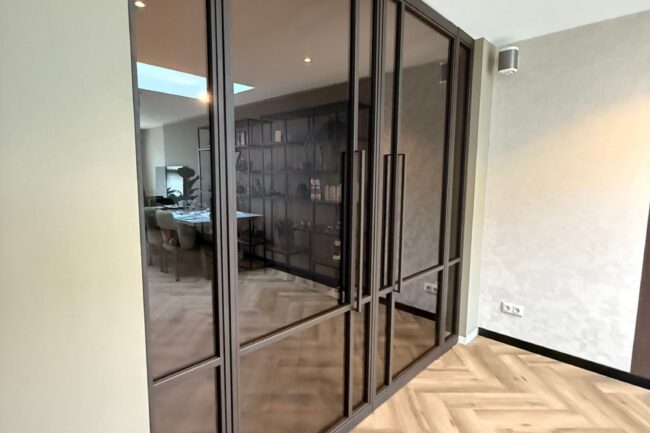 Op maat gemaakte stalen deuren in een chique bruintint met getint veiligheidsglas en strakke verticale handgrepen.