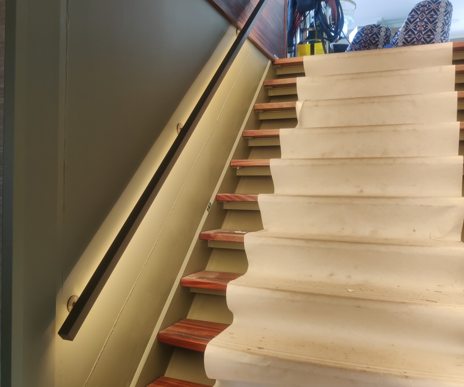 Bronzen stalen trapleuning met geïntegreerde ledverlichting en bijpassende roomdivider met geribbeld glas in een luxe scheepsinterieur.