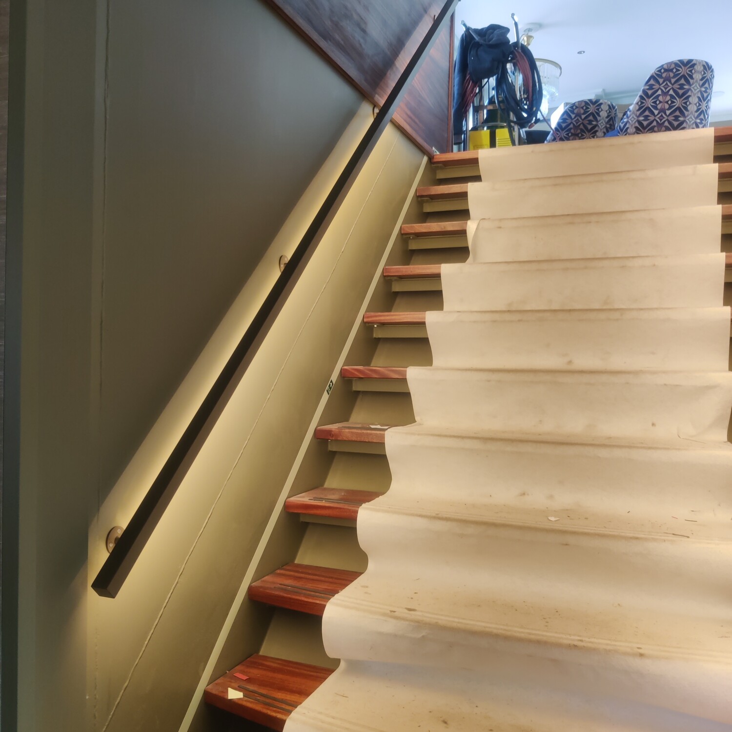 Bronzen stalen trapleuning met geïntegreerde ledverlichting en bijpassende roomdivider met geribbeld glas in een luxe scheepsinterieur.